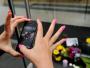 Kobieta fotografuje swym iPhonem kwiaty złożone na George Street w Sydney
